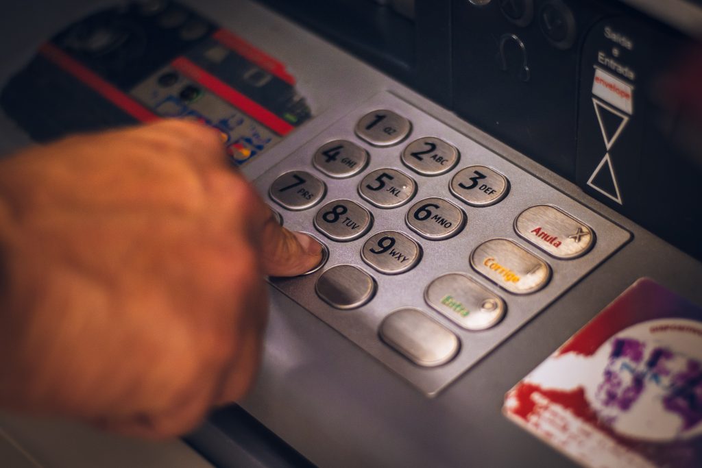 Person adding PIN to ATM machine to withdraw cash